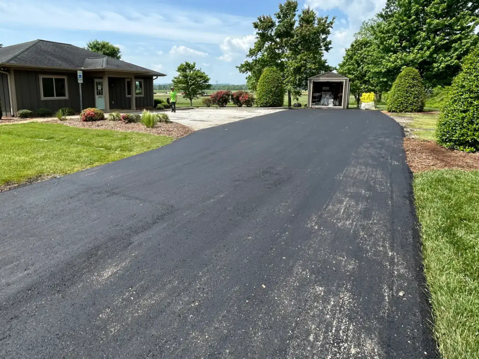 After: the same driveway paved in smooth black asphalt