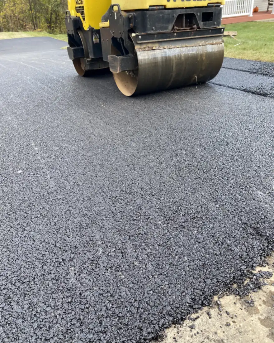 Steel drum roller compacting a fresh hot-mix asphalt driveway